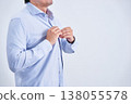A faceless Japanese man in his 30s is changing his dress shirt while facing diagonally in front of a white background. 138055578