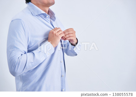 一位面容模糊的日本男子，三十多歲，在白色背景前斜對著自己，正在換襯衫。 138055578