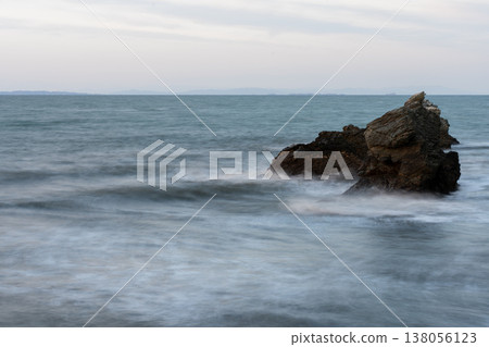 Rock shore with white waves washing over it 138056123