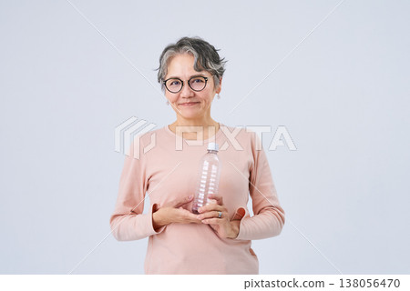 Senior woman drinking water from a plastic bottle Senior woman drinking water from a plastic bottle 138056470
