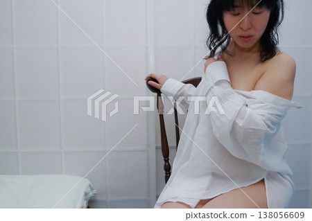 Woman in a white dress sitting on a chair Woman in a white dress sitting on a chair 138056609