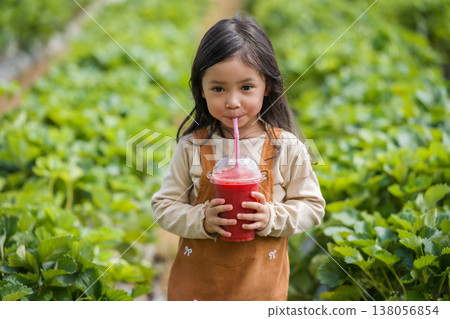 preschool child girl drinking a fresh strawberry smoothie in farm preschool child girl drinking a fresh strawberry smoothie in farm 138056854