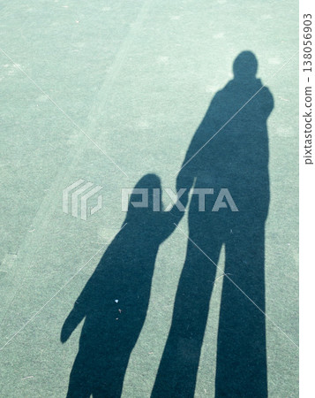 The shadow of a one-year-old child and an adult holding hands 138056903