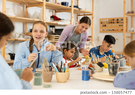 Teenage girl speaking to a circle member while processing ceramic items 138057477