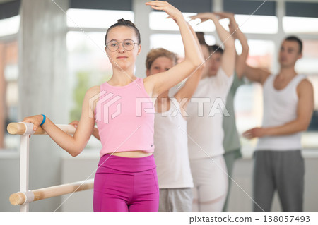 Girl during group class perform third position under male teacher guidance. Girl during group class perform third position under male teacher guidance. 138057493