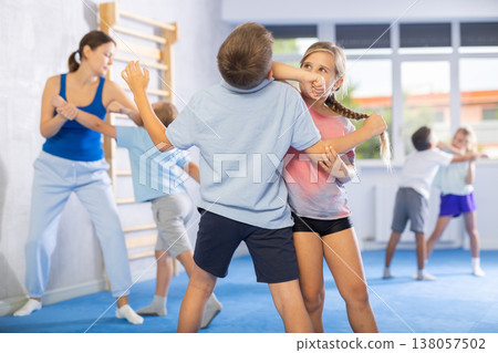 Kids in sportswear exercising self-protection techniques in pair during class Kids in sportswear exercising self-protection techniques in pair during class 138057502