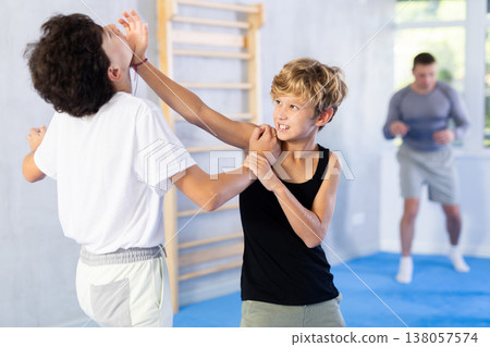 Boy and girl train to perform works out blow to jaw at opponent, while learning self-defense Boy and girl train to perform works out blow to jaw at opponent, while learning self-defense 138057574