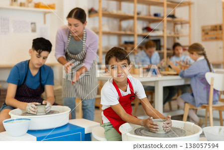 Boy in an apron working at a potter's wheel 138057594