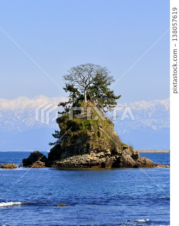 Onna-iwa Rock and the snow-covered Tateyama mountain range as seen from Amaharashi Coast in Takaoka City, Toyama Prefecture. 138057619