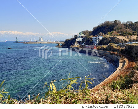 Onna-iwa Rock and the snow-covered Tateyama mountain range as seen from Amaharashi Coast in Takaoka City, Toyama Prefecture. 138057635
