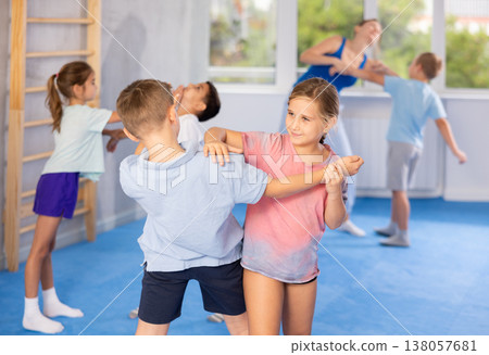 Boys and girls in gym perform basic elements of krav maga self-defense system. Boys and girls in gym perform basic elements of krav maga self-defense system. 138057681