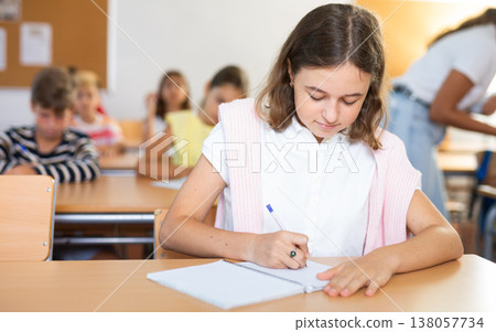 Schoolgirl are sitting at their desks and listens carefully to the teacher Schoolgirl are sitting at their desks and listens carefully to the teacher 138057734