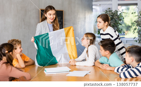 School teacher tells students about Ireland and holds Ireland flag in her hands. School teacher tells students about Ireland and holds Ireland flag in her hands. 138057737