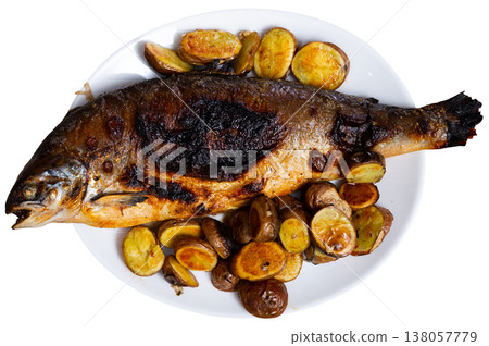 Roasted salmon carcass is accompanied by baked potato halves in their jacket 138057779