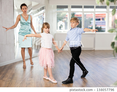 Kids learning cha-cha with female dance instructor in choreography studio Kids learning cha-cha with female dance instructor in choreography studio 138057796