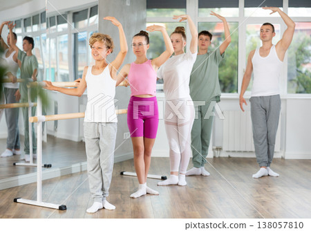 Teenage boys and girls practicing third position of ballet in dancehall 138057810