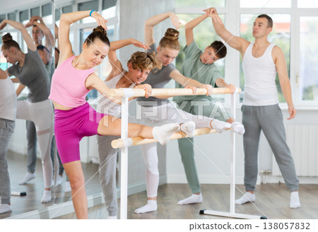 Teenage boys and girls practicing leg stretching exercise during ballet classes Teenage boys and girls practicing leg stretching exercise during ballet classes 138057832