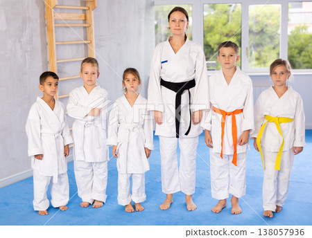 Portrait of female karate or judo coach with her students little children in gym Portrait of female karate or judo coach with her students little children in gym 138057936