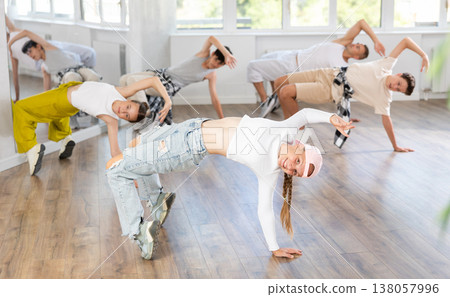 Girl in baseball cap with two hair pigtails with group of teenage friends, learn to dance hip hop Girl in baseball cap with two hair pigtails with group of teenage friends, learn to dance hip hop 138057996