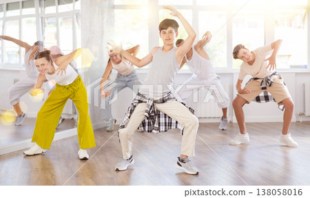 Teen guy together with group of teenage friends, learn to dance hip hop in choreographic hall. 138058016