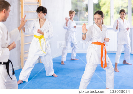 Children students repeat position and perform sequence of punches and painful techniques kata 138058024