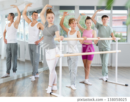 Teenage boys and girls practicing third position of ballet in dancehall Teenage boys and girls practicing third position of ballet in dancehall 138058025