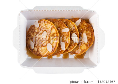 Sweet pancake with syrup topping and almond flake in white paper take out box top view close up flat lay delicious breakfast food with no people Sweet pancake with syrup topping and almond flake in white paper take out box top view close up flat lay delicious breakfast food with no people 138058167
