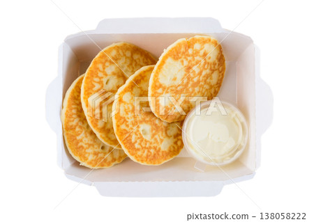 Sweet thick pancake with sour cream in white paper take out box on white background top view close up flat lay with copy space delicious breakfast 138058222