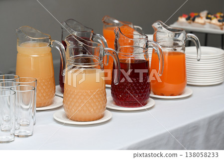 Assorted catering beverage station with fruit juice and berry mors in glass pitcher on buffet table for event with no people and copy space for menu Assorted catering beverage station with fruit juice and berry mors in glass pitcher on buffet table for event with no people and copy space for menu 138058233