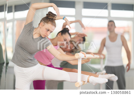Teen ballet students prepare for classes, near ballet bare stretch legs under man teacher guidance 138058861