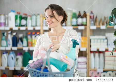 Young woman with full basket choosing something in supermarket 138058883