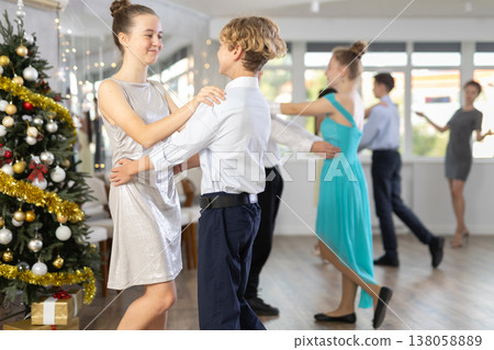 Teen boy and girl dancing waltz in couple during lesson at studio in New Year atmosphere Teen boy and girl dancing waltz in couple during lesson at studio in New Year atmosphere 138058889