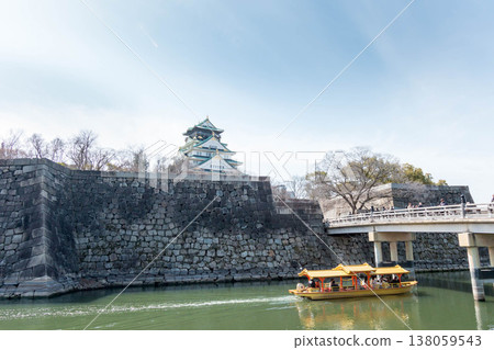 Osaka Castle's main tower stands out against the blue sky, and a golden pleasure boat cruises the moat. Osaka Castle's main tower stands out against the blue sky, and a golden pleasure boat cruises the moat. 138059543