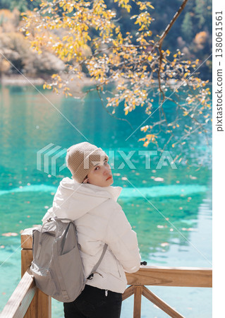 Happy woman traveler travel in jiuzhaigou national park in Sichuan, China. Tourist sightseeing Five Flower lake and snow mountain in Autumn season. Famous Landmark and Vacation near Chengdu, China Happy woman traveler travel in jiuzhaigou national park in Sichuan, China. Tourist sightseeing Five Flower lake and snow mountain in Autumn season. Famous Landmark and Vacation near Chengdu, China 138061561