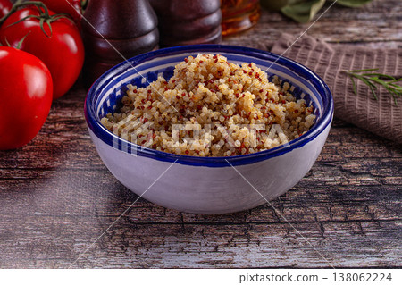 Healthy cooked tri-color quinoa in a bowl with fresh tomatoes and rosemary on a rustic wooden table Healthy cooked tri-color quinoa in a bowl with fresh tomatoes and rosemary on a rustic wooden table 138062224
