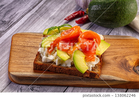 Smoked salmon and avocado toast with cream cheese on a rustic wooden cutting board. 138062246