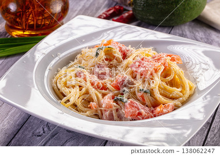 Creamy spaghetti pasta with salmon and grated parmesan cheese on a rustic wooden table. Creamy spaghetti pasta with salmon and grated parmesan cheese on a rustic wooden table. 138062247
