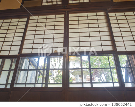 A Japanese garden, bathed in sunlight, is framed by snow-viewing shoji screens. A Japanese garden, bathed in sunlight, is framed by snow-viewing shoji screens. 138062441