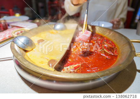 Woman tourist eating traditional hot pot or mala spicy soup in restaurant. Popular foods for tourist eating in Chengdu, Chongqing and China. Chinese Asia and Sichuan foods concept Woman tourist eating traditional hot pot or mala spicy soup in restaurant. Popular foods for tourist eating in Chengdu, Chongqing and China. Chinese Asia and Sichuan foods concept 138062718