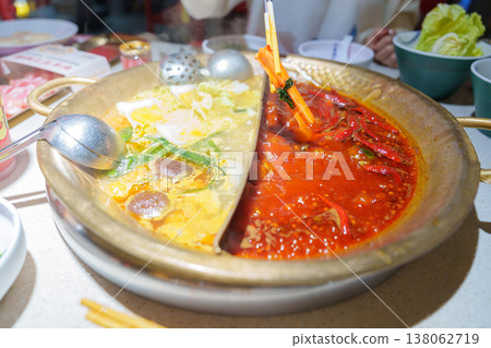 Woman tourist eating traditional hot pot or mala spicy soup in restaurant. Popular foods for tourist eating in Chengdu, Chongqing and China. Chinese Asia and Sichuan foods concept Woman tourist eating traditional hot pot or mala spicy soup in restaurant. Popular foods for tourist eating in Chengdu, Chongqing and China. Chinese Asia and Sichuan foods concept 138062719