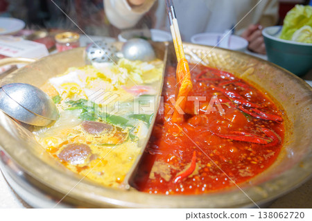 Woman tourist eating traditional hot pot or mala spicy soup in restaurant. Popular foods for tourist eating in Chengdu, Chongqing and China. Chinese Asia and Sichuan foods concept Woman tourist eating traditional hot pot or mala spicy soup in restaurant. Popular foods for tourist eating in Chengdu, Chongqing and China. Chinese Asia and Sichuan foods concept 138062720