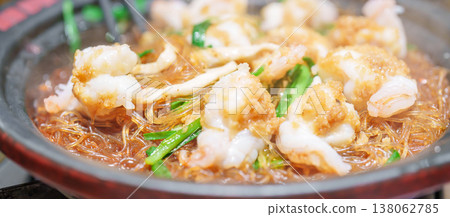 Woman tourist eating baked shrimp with glass noodles and garlic in restaurant. Popular foods for tourist eating in Chengdu, China. Chinese Asia and Sichuan foods concept Woman tourist eating baked shrimp with glass noodles and garlic in restaurant. Popular foods for tourist eating in Chengdu, China. Chinese Asia and Sichuan foods concept 138062785