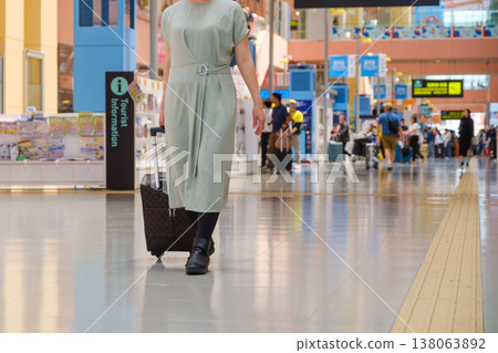 女旅客走過機場大廳:遊客拖著行李箱走來走去。 女旅客走過機場大廳:遊客拖著行李箱走來走去。 138063892