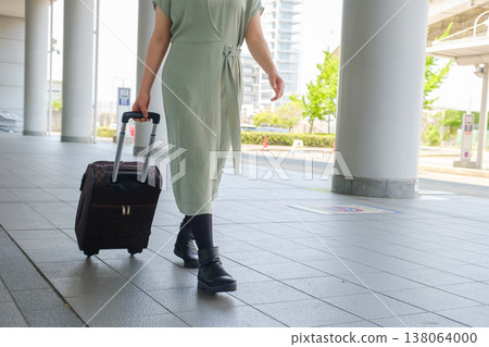 一位女遊客走過城市廣場：她的行李箱和都市旅行景象。 138064000