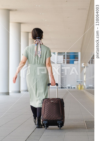A female tourist walking through a city concourse: her suitcase and the urban scene of travel. A female tourist walking through a city concourse: her suitcase and the urban scene of travel. 138064003