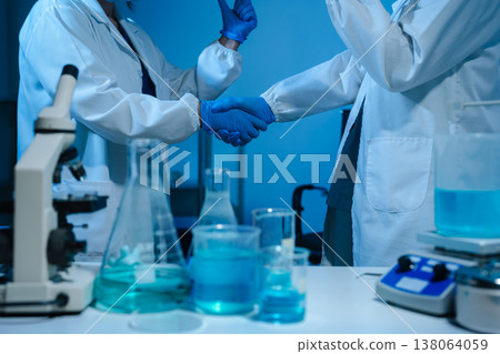 Scientists Shaking Hands in Laboratory Representing Teamwork, Success, and Medical Research Collaboration. Scientists Shaking Hands in Laboratory Representing Teamwork, Success, and Medical Research Collaboration. 138064059