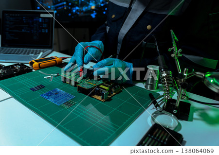 Computer Hardware Technician Repairing Motherboard with Soldering Iron in Electronics Lab. Computer Hardware Technician Repairing Motherboard with Soldering Iron in Electronics Lab. 138064069