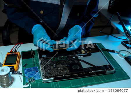 Computer Hardware Technician Repairing Motherboard with Soldering Iron in Electronics Lab. 138064077