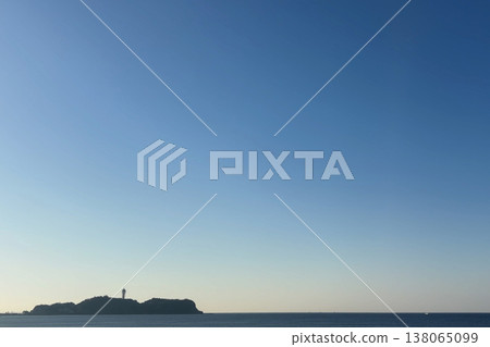 An island with a lighthouse, a blue sky, and a calm sea horizon. An island with a lighthouse, a blue sky, and a calm sea horizon. 138065099