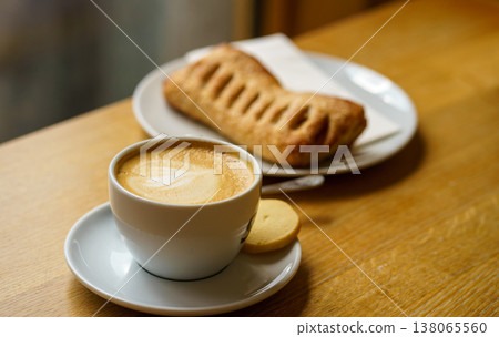 Cappuccino with fresh pastry on table, soft warm light, cafe breakfast, relaxing lifestyle, sweet snack and coffee moment Cappuccino with fresh pastry on table, soft warm light, cafe breakfast, relaxing lifestyle, sweet snack and coffee moment 138065560